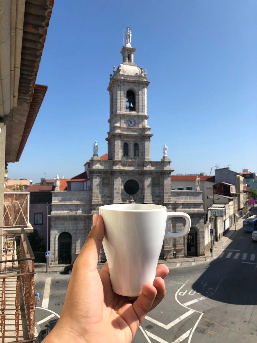 a person holding a cup in front of the carmo church