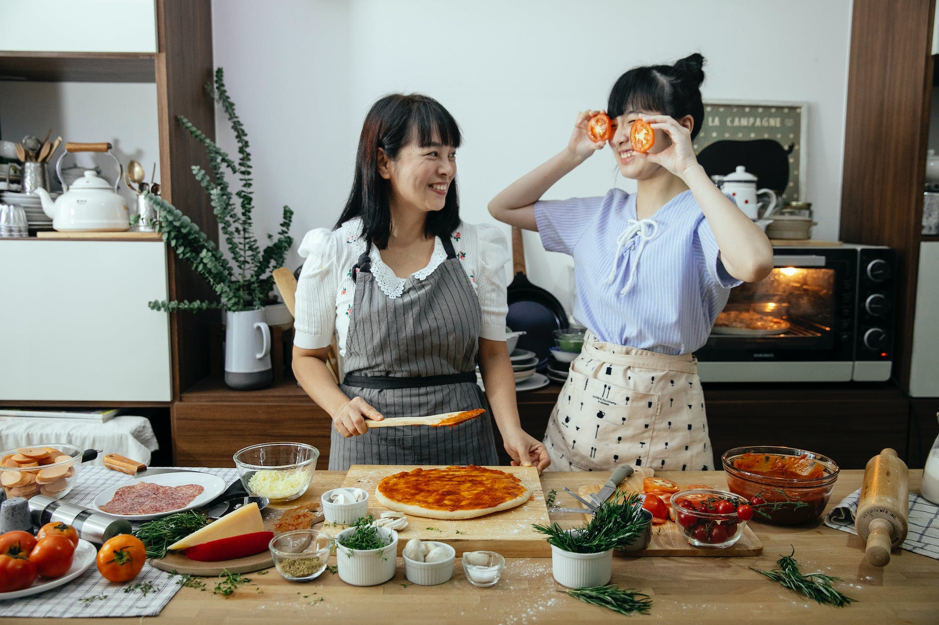 positive women having fun cooking pizza